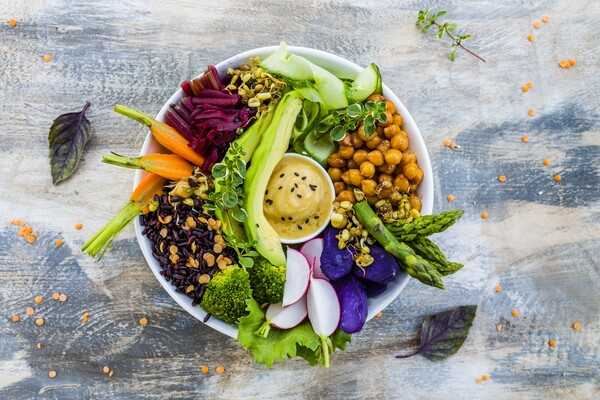 A colourful square bowl with fresh vegetables and balanced ingredients